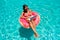 Young woman swims in the sea in a swimming circle. Girl resting in the pool on an inflatable circle with a computer, top