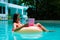 Young woman swims in the sea in a swimming circle. Girl resting in the pool on an inflatable circle with a computer, top