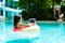 Young woman swims in the sea in a swimming circle. Girl resting in the pool on an inflatable circle with a computer, top