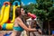 Young woman in a swimsuit drinks water from a bottle. Charming tanned athletic woman stands in the sun in a swimsuit and drinks