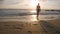 Young woman in swimsuit goes on sea beach to bathe at sunset. Beautiful young girl walking on shore to the ocean during