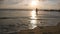 Young woman in swimsuit goes on sea beach to bathe at sunset. Beautiful young girl walking on shore to the ocean during