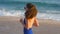 Young woman in swimsuit running on sea beach and listening music. Girl jogging along ocean shore. Female sportsman