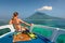 Young woman in swimsuit sit on boat looking to a island