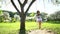 Young woman swinging on wooden swing with little pretty girl in dress. Static