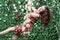 Young woman swings on swing overgrown with flowers