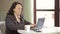 Young woman at a table in a cafe, working behind a laptop and drinking coffee. Slow mo.