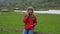 Young woman takes a phone call while standing in a typical Irish scenery