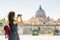 Young woman takes a picture of Cathedral of St. Peter in Rome