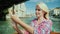 Young woman takes pictures of beautiful views of Venice in Italy. She sails on a boat on a Grand Canal cruise.