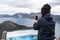 A young woman takes pictures with her smartphone of the views of Crater Lake in the background