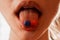 Young woman takes a pill. Blu and orange pill on young female tongue