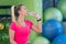 A young woman taking a break at the gym sitting on a pilates ball with a bottle of water