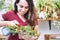 A young woman taking care of her garden, spraying water onto houseplants in pots at home