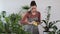 Young woman taking care of the plants and flowers in the flowerpot by wiping and cleaning dust and dirt from the leaf or leaves