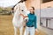 Young woman taking horse to outdoor riding arena for training