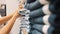 Young woman taking pair of blue denim jeans from stacks in clothing shop. Female hands choosing correct pants size in shopping