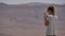 Young woman taking panoramic photo of the desert crater on her phone