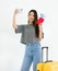 Young woman taking a photo with a passport, airline ticket, and suitcase