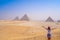 Young woman taking photos with Pyramids of Giza view