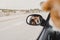 Young woman taking a picture with camera on rear mirror of her cute small jack russell dog watching by the window. Ready to travel