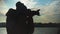 Young woman taking pictures of the sunset on the background of the sea, city and sky.