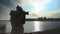 Young woman taking pictures of the sunset on the background of the sea, city and sky.