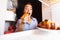 Young woman taking plate with croissants from fridge