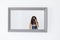 Young woman taking a self portrait in the mirror at home. White walls and background. Reflex camera covering her face. Lifestyle