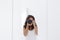 Young woman taking a self portrait in the mirror at home. White walls and background. Reflex camera covering her face. Lifestyle