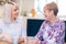 Young Woman Taking Time To Visit Senior Female Neighbor And Talk