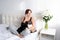 Young woman talking on the phone with her two cats on white bedroom with Flowers