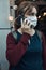 Young woman talking on phone standing in a front of restaurant downtown wearing the face mask to avoid virus infection