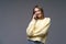 Young woman talking on the phone in yellow sweater on gray background