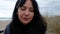 Young woman talking with sad and smiling expression on the beach during a cloudy moody winter day. young latino woman with dark