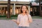 Young woman talking by sartphone outside, wearing blouse.