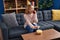 Young woman talking on smartphone eating chips potatoes at home