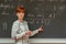 Young woman teacher in college. Instruction in a university classroom. Blackboard described by chalk. Projection from