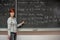 Young woman teacher in college. Instruction in a university classroom. Blackboard described by chalk. Projection from