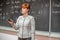 Young woman teacher in college. Instruction in a university classroom. Blackboard described by chalk. Projection from