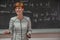 Young woman teacher in college. Instruction in a university classroom. Blackboard described by chalk. Projection from