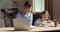 Young woman teacher educator nanny wears glasses, sits with little girl at table, checks homework completed work of