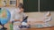 Young woman teacher plays games on the phone while sitting in the classroom. The teacher writes sms. Slow motion