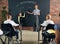 Young woman, teacher standing by blackboard with little girl, child and teaching math at school. Attentive kids