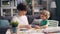 Young woman teaching her little son to make paper collage at table at home