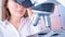 Young woman technician is examining a histological sample, a biopsy in the laboratory of cancer research