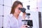 Young woman technician is examining a histological sample, a biopsy in the laboratory of cancer research