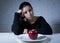 Young woman or teen looking apple fruit on dish as symbol of crazy diet in nutrition disorder