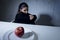 Young woman or teen looking apple fruit on dish as symbol of crazy diet in nutrition disorder