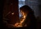 Young woman, teenage girl, student, schoolgirl sits at a desk in a dark room under the light of a table lamp